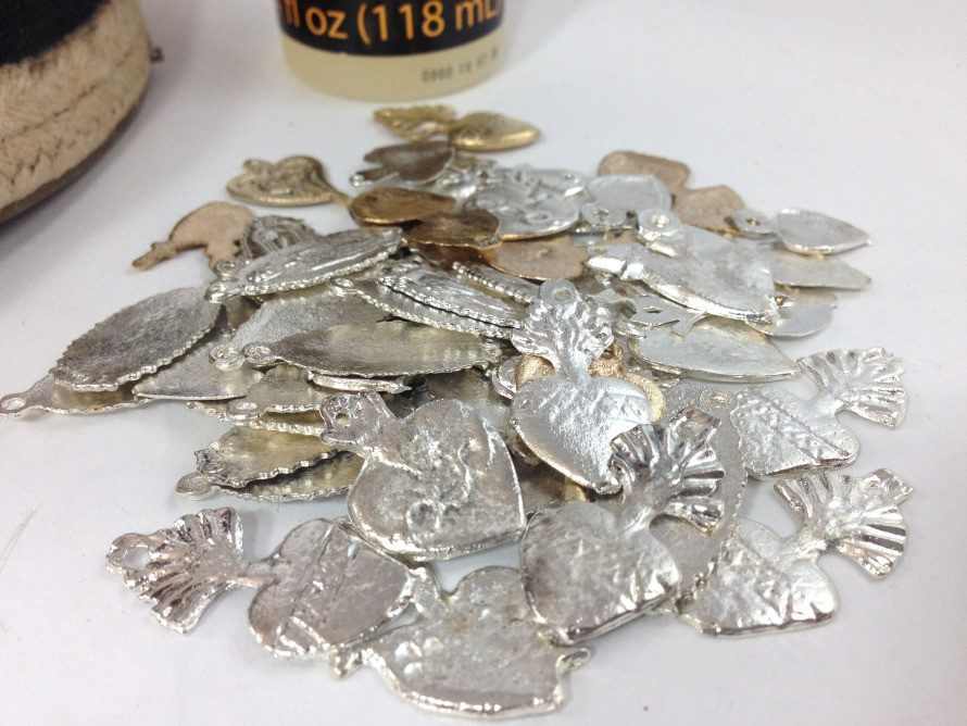 a pile of pewter milagros